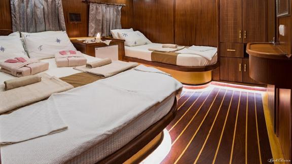 Comfortable cabin with double and single bed, stylish wood panelling and discreet LED lighting.